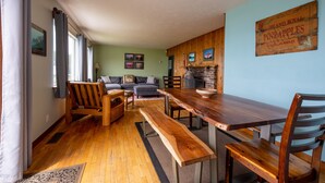 A cozy living room with a wooden bench, a sofa, and a dining table with chairs. - Ocean Front Home in the Heart of Newport! (Newport)