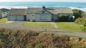 A single-story house with a garage, a small porch, and a view of the ocean. - Ocean Front Home in the Heart of Newport! (Newport)
