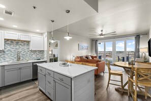 Enjoy a spacious kitchen with a marble island and pendant lighting, complemented by a cozy living area with a sofa and dining table.