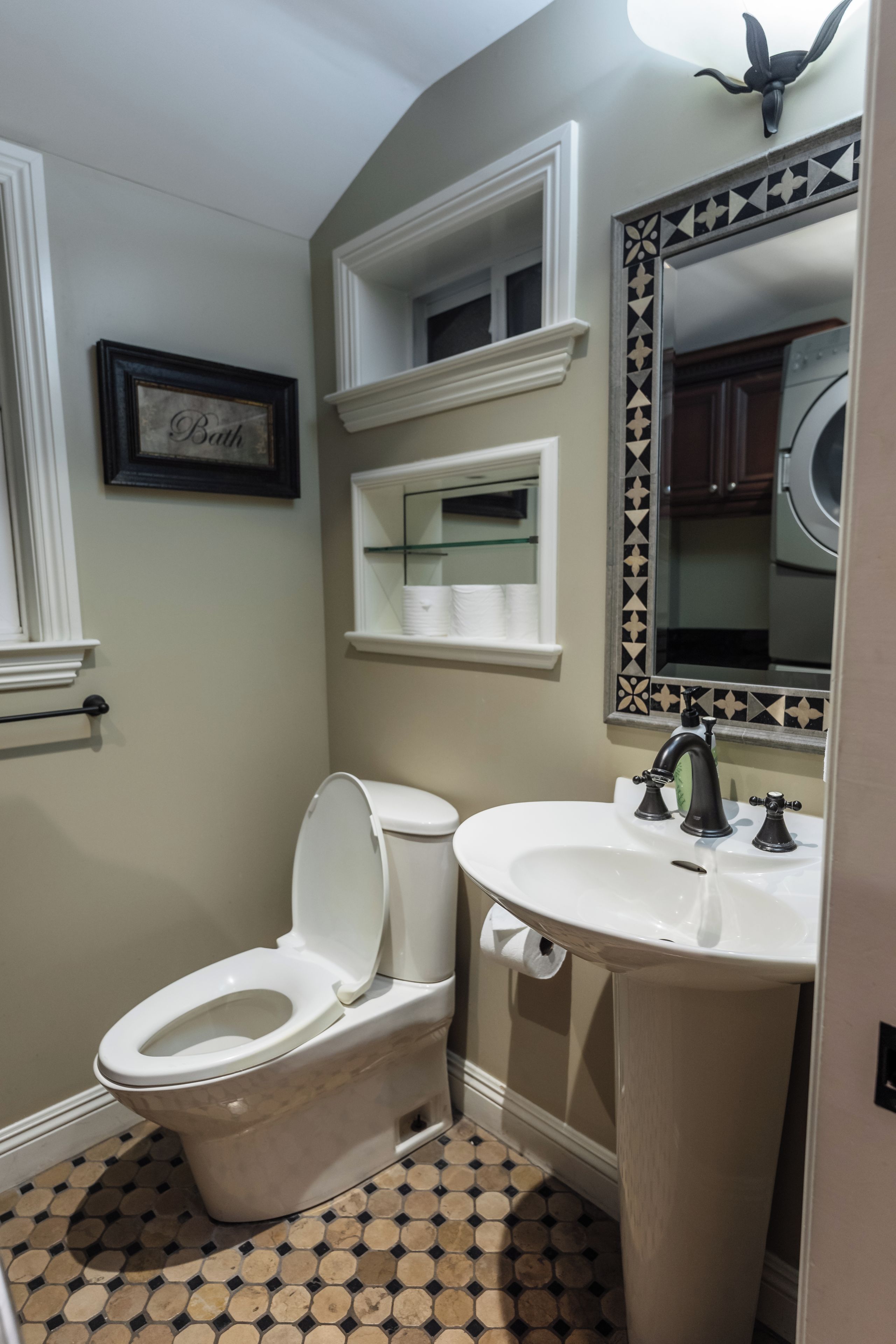 Une salle de bain avec des toilettes, un lavabo et un miroir.