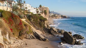 A coastal view with a sandy beach, rocky shoreline, and a staircase leading down to the water. - Beautiful Ocean View! Steps to Sand! Private Home with 3 Car Driveway! (Laguna Beach)