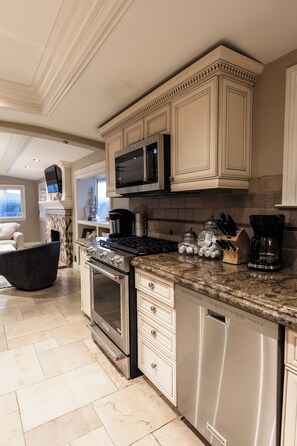 A modern kitchen with stainless steel appliances, a granite countertop, and white cabinetry.