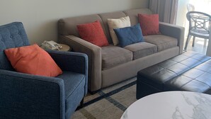 Un salon comprenant un canapé, des fauteuils, une table basse et un tapis à motifs.