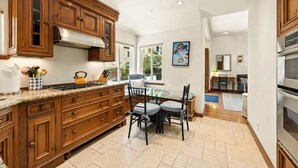 Une cuisine spacieuse dotée de meubles en bois, d’un plan de travail en granit et d’un coin repas avec une table et des chaises.