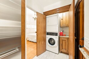 Une petite buanderie équipée d’un lave-linge, d’un sèche-linge et d’armoires en bois.