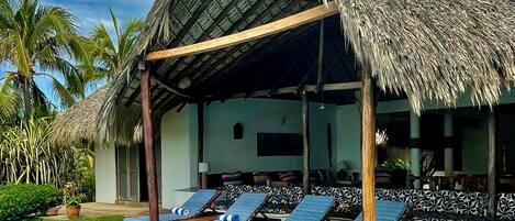 A poolside area with lounge chairs and a thatched-roof structure.