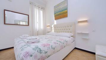 Ein Schlafzimmer mit Bett, Spiegel, Gemälde und Nachttisch.
