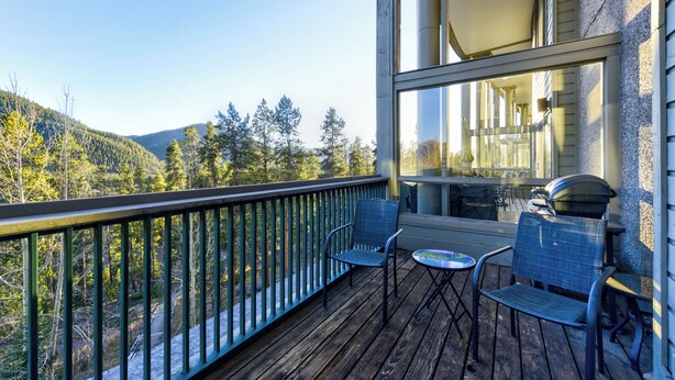 A wooden deck with two chairs and a small table, overlooking a forested hillside. - Amazing Views-Free shuttle, Lodge access pool/gym. (Keystone)