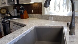 A kitchen with a stainless steel sink, a microwave, and a knife block.