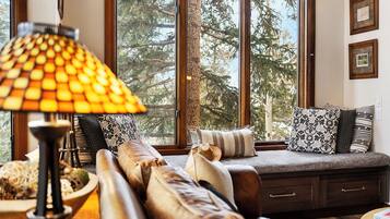 Ein gemütliches Wohnzimmer mit großem Fenster, einer Couch und einer Lampe.