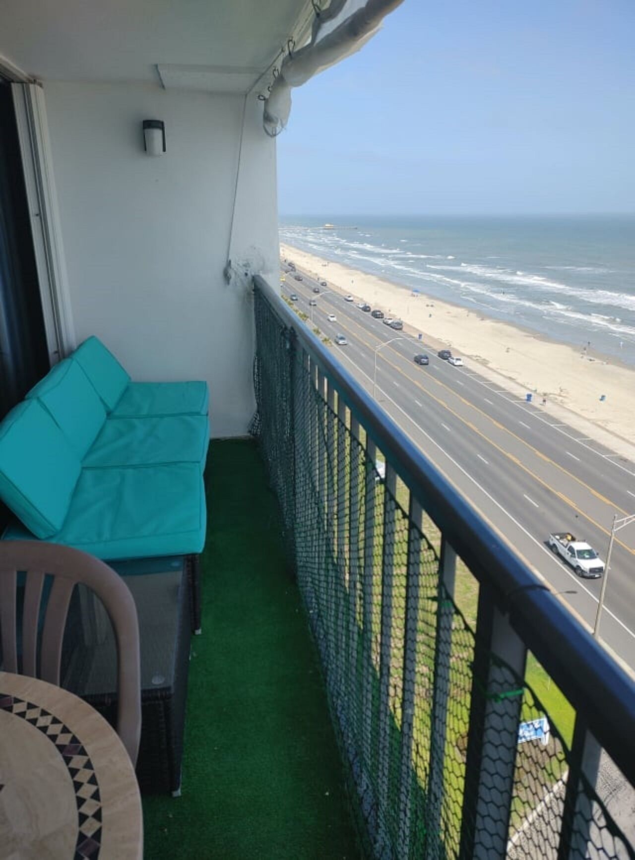 A balcony with a view of the beach and a road.