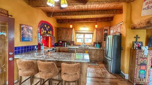 Una cocina con armarios de madera, encimera de granito y una isla grande con taburetes de bar.