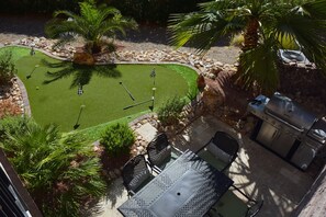 A patio with a grill, seating, and a small lawn area.
