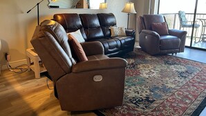 Una sala de estar con un sofá de cuero, un sillón reclinable, un tapete estampado y un espejo grande.