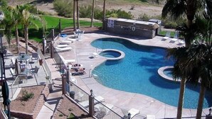 Una piscina con un diseño curvo singular, rodeada de sillas de descanso y una zona de barbacoa.
