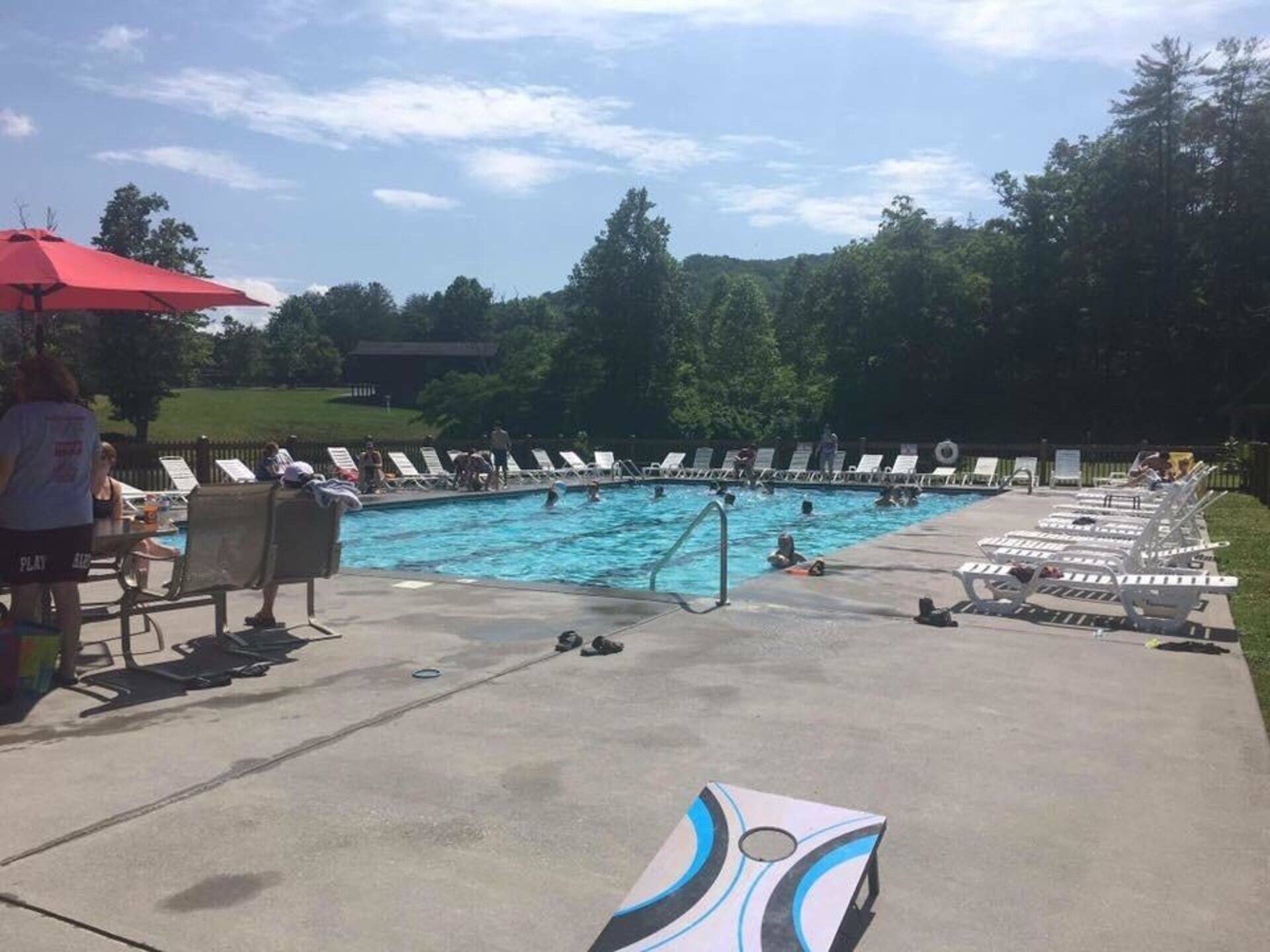 Ein Poolbereich mit Liegestühlen und einem roten Sonnenschirm.