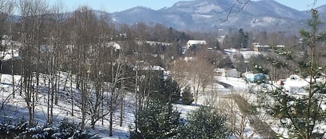 Paisaje nevado con casas y montañas al fondo.