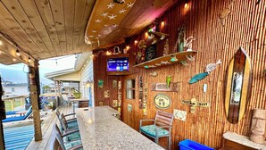 Una zona de bar con pared de madera, una pantalla de televisión y varios adornos.
