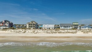 Una propiedad frente a la playa con varias casas, una playa de arena y olas del océano.