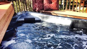Un jacuzzi con un muelle de madera y una valla de madera al fondo.