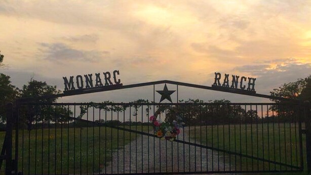 Una entrada cerrada con la leyenda "Monarc Ranch" y un símbolo de estrella.