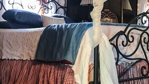Una cama con dosel, falda de cama a cuadros y almohadas.