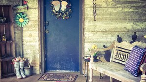 Un interior rústico con un banco de madera, un letrero de bienvenida y una puerta decorada con un detalle de mariposa.
