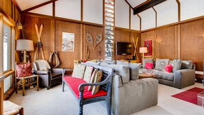 Un salon confortable avec un ensemble de canapés, un fauteuil rouge et un téléviseur.