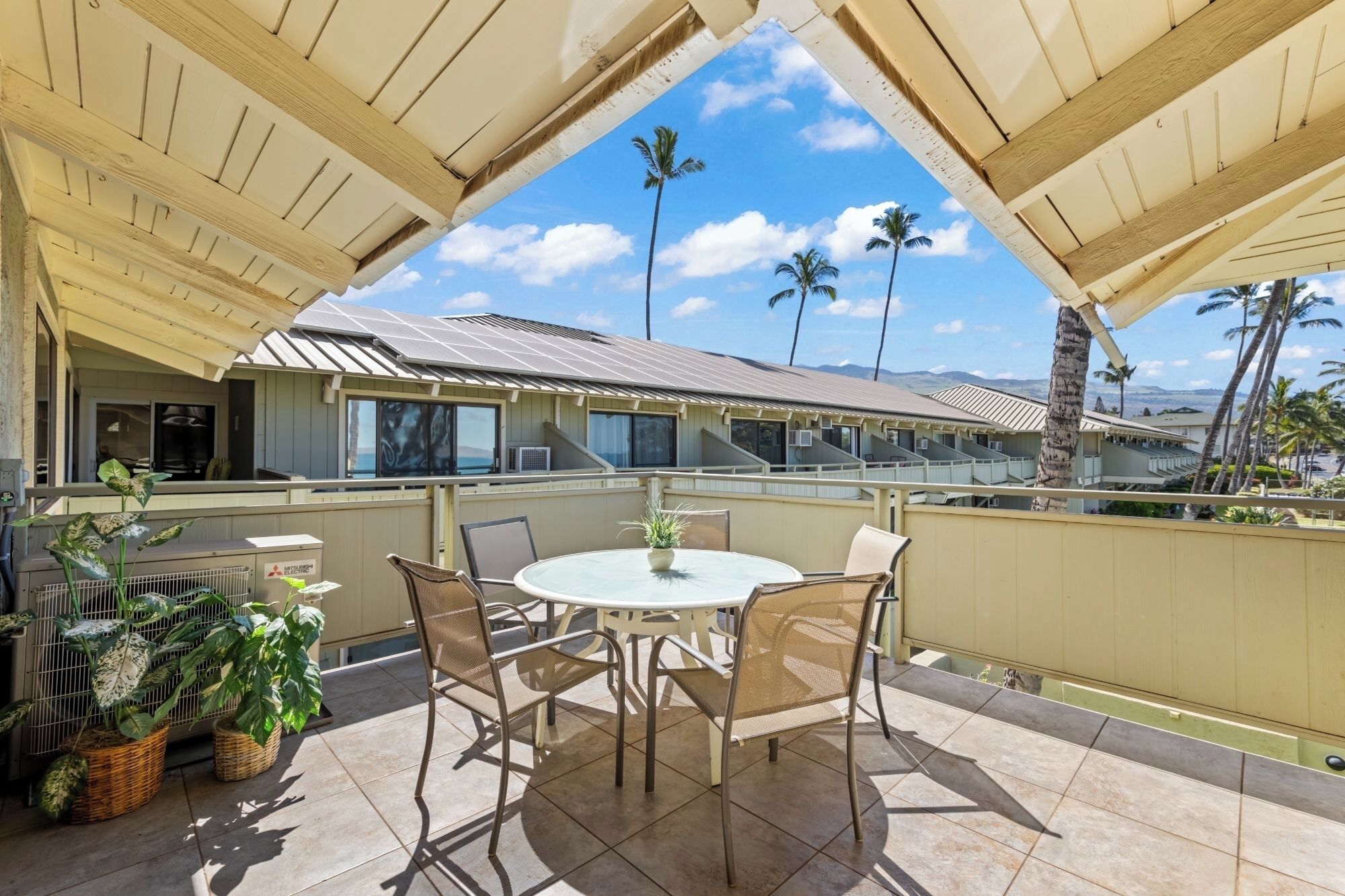 An outdoor patio with a round table and chairs, surrounded by potted plants.
