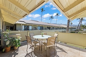 An outdoor patio with a round table and chairs, surrounded by potted plants.