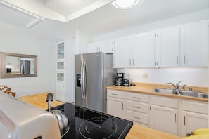 A modern kitchen with white cabinets, a stainless steel refrigerator, a coffee maker, and a toaster.