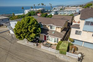 A residential area with houses, a white picket fence, and a large tree.