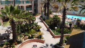 A pool area with lounge chairs, surrounded by palm trees and a garden with various plants. - PRICE REDUCTION! BEACH FRONT CONDO! 
San Diego-Imperial Beach-Coronado (Imperial Beach)