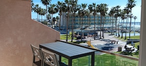 Un balcon avec vue sur un hôtel, des palmiers et une plage.