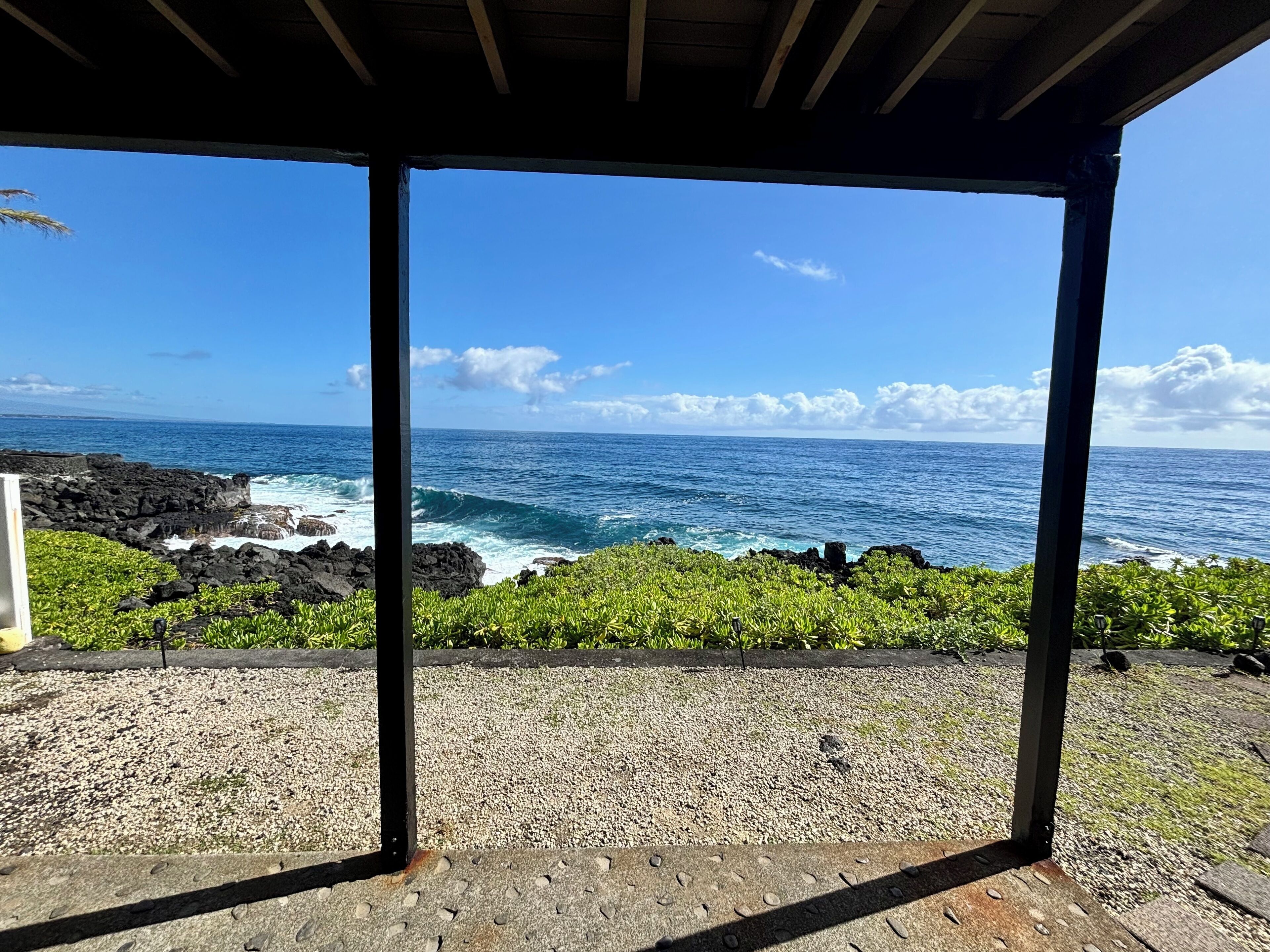 A covered outdoor area with a view of the ocean and rocky coastline.