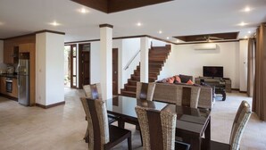 A spacious living area with a dining table, chairs, a staircase, and a television. - 3 Bedroom Villa TG25 Beach Front Resort SDV282-By Samui Dream Villas (Koh Samui)