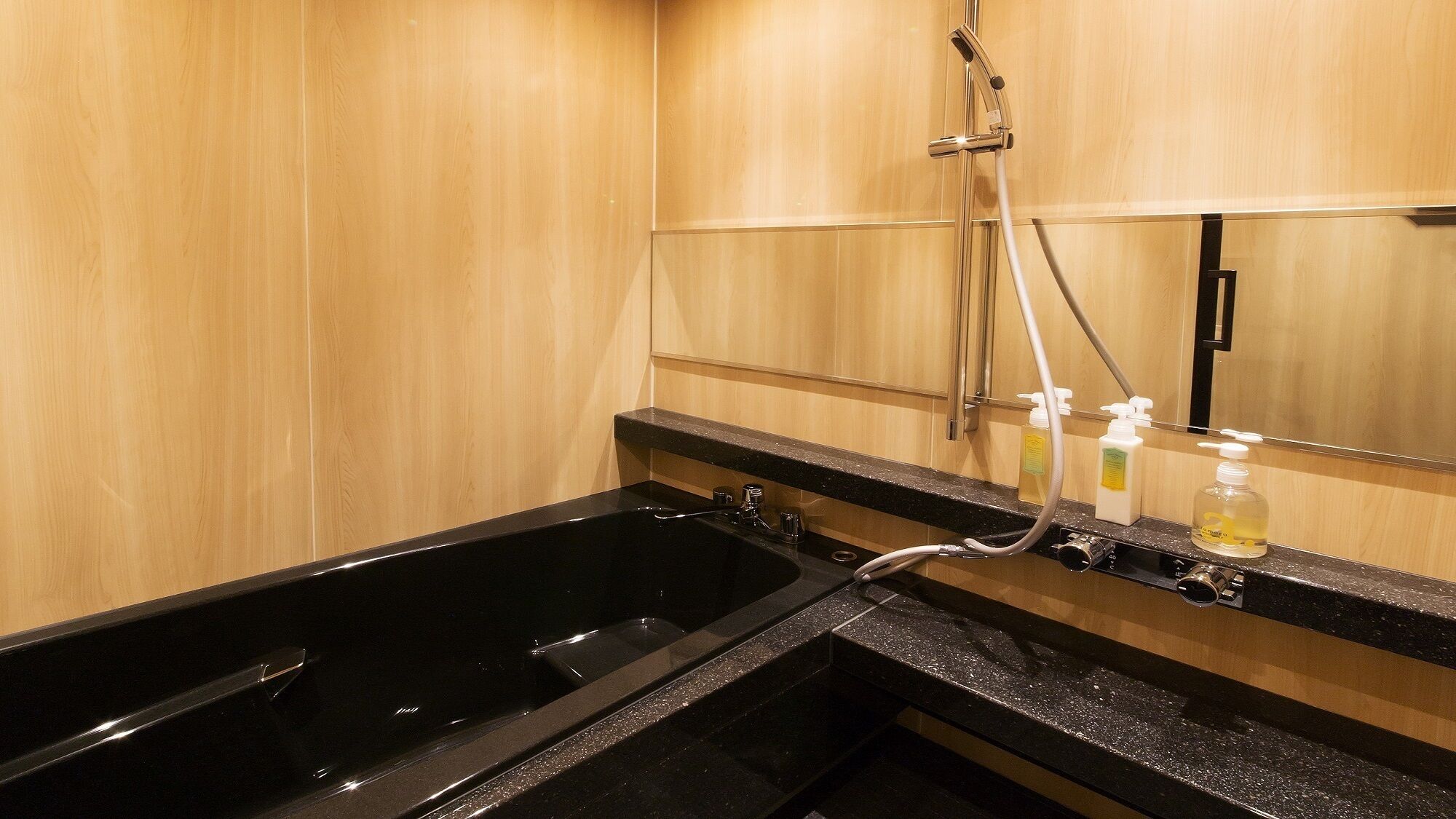 A bathroom with a black bathtub, a shower, and a mirror above the sink.