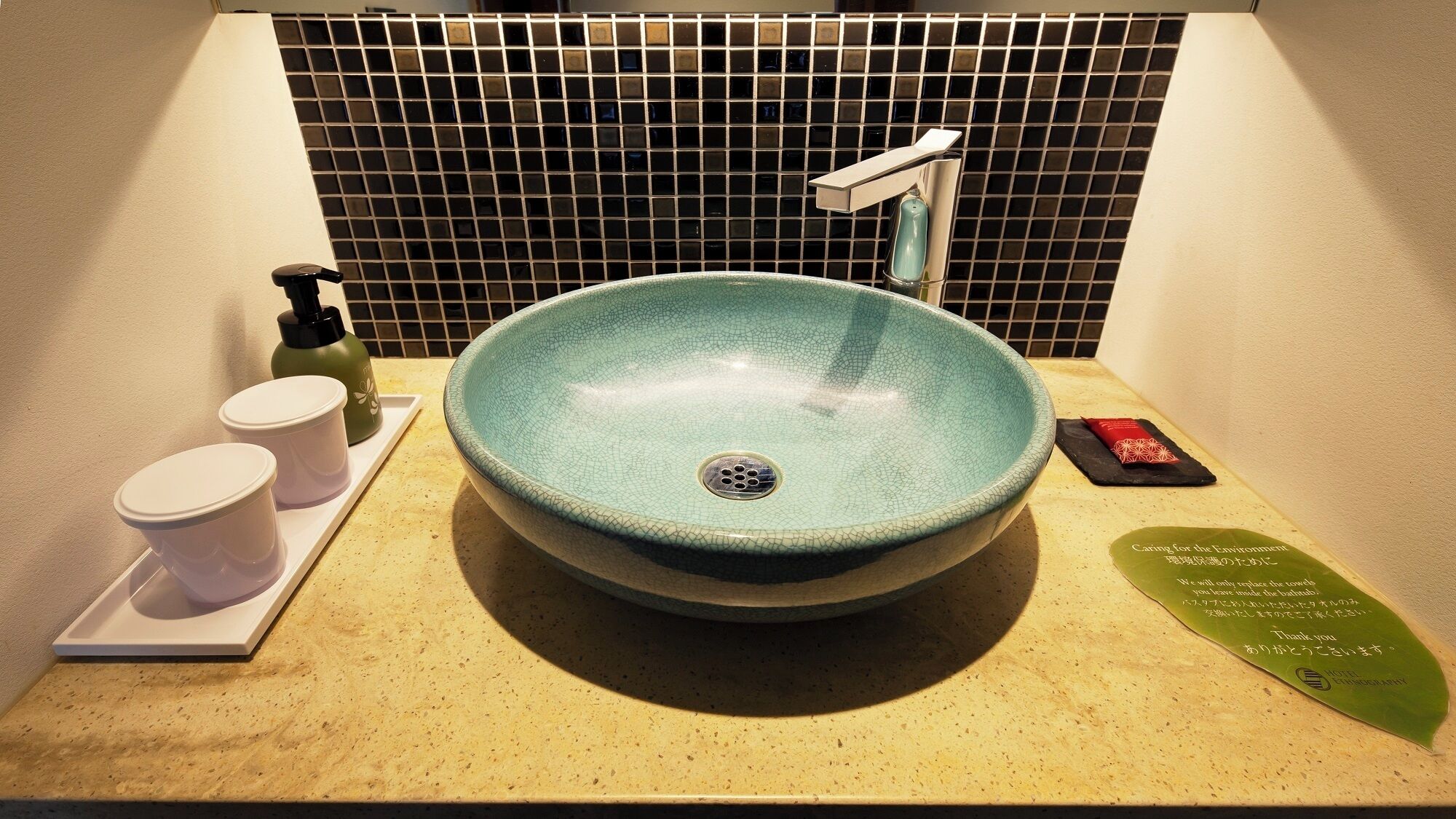 A bathroom sink with a modern design, a faucet, and a soap dispenser on the counter.