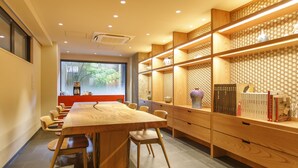 Een moderne vergaderruimte met een houten tafel, stoelen en boekenkasten.
