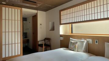 Een hotelkamer met een bed, een stoel, een raam met uitzicht en een traditioneel Japans shoji-scherm.