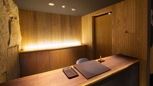 Een receptiebalie met een houten afwerking, een klein dienblad en een muur met een structuur.