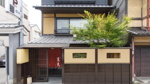 Een traditionele Japanse woning met een schuifdeur, een kleine tuin en een geparkeerde auto ervoor.