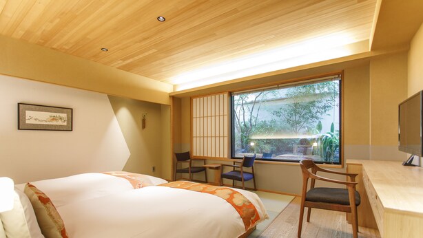 Een hotelkamer met een bed, bureau, stoelen en een groot raam.