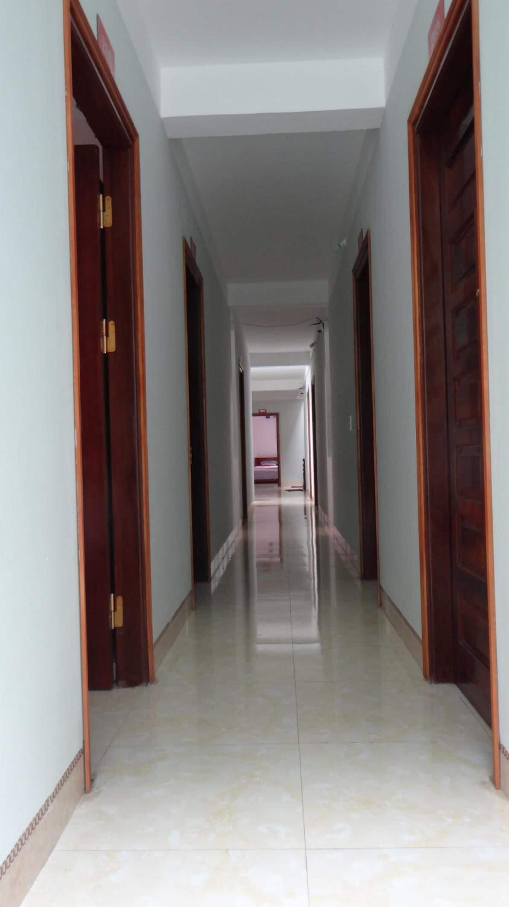 A long, narrow hallway with wooden doors on both sides and a tiled floor.