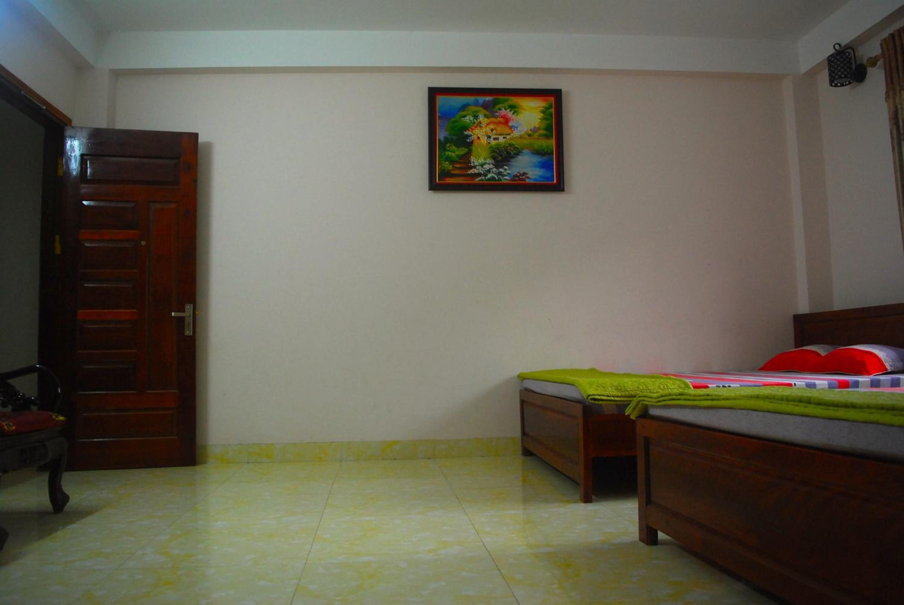Een slaapkamer met een bed, een deur en een schilderij aan de muur.