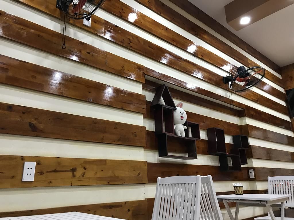 A room with wooden panel walls, a white chair, a table, and a shelf with a stuffed toy.