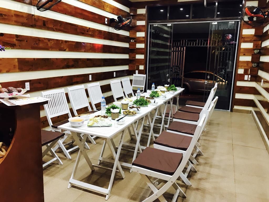 A long dining table with white chairs, set with plates, bowls, and bottles.