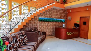 Eine Hotelhalle mit Treppe, einer Rezeption und einer Sofaecke.