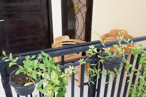 A balcony with potted plants and wooden chairs. - Akatara Stay Jimbaran (Jimbaran)