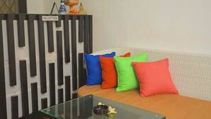 A reception area with a sofa, colorful cushions, a glass coffee table, and a reception desk. - Akatara Stay Jimbaran (Jimbaran)